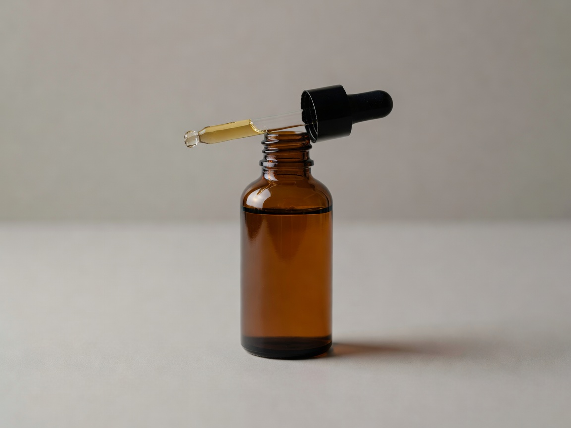 Amber glass vitamin C serum bottle with dropper on a neutral surface